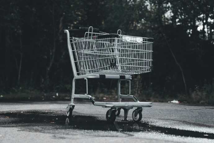 A shopping cart sitting on the side of a road